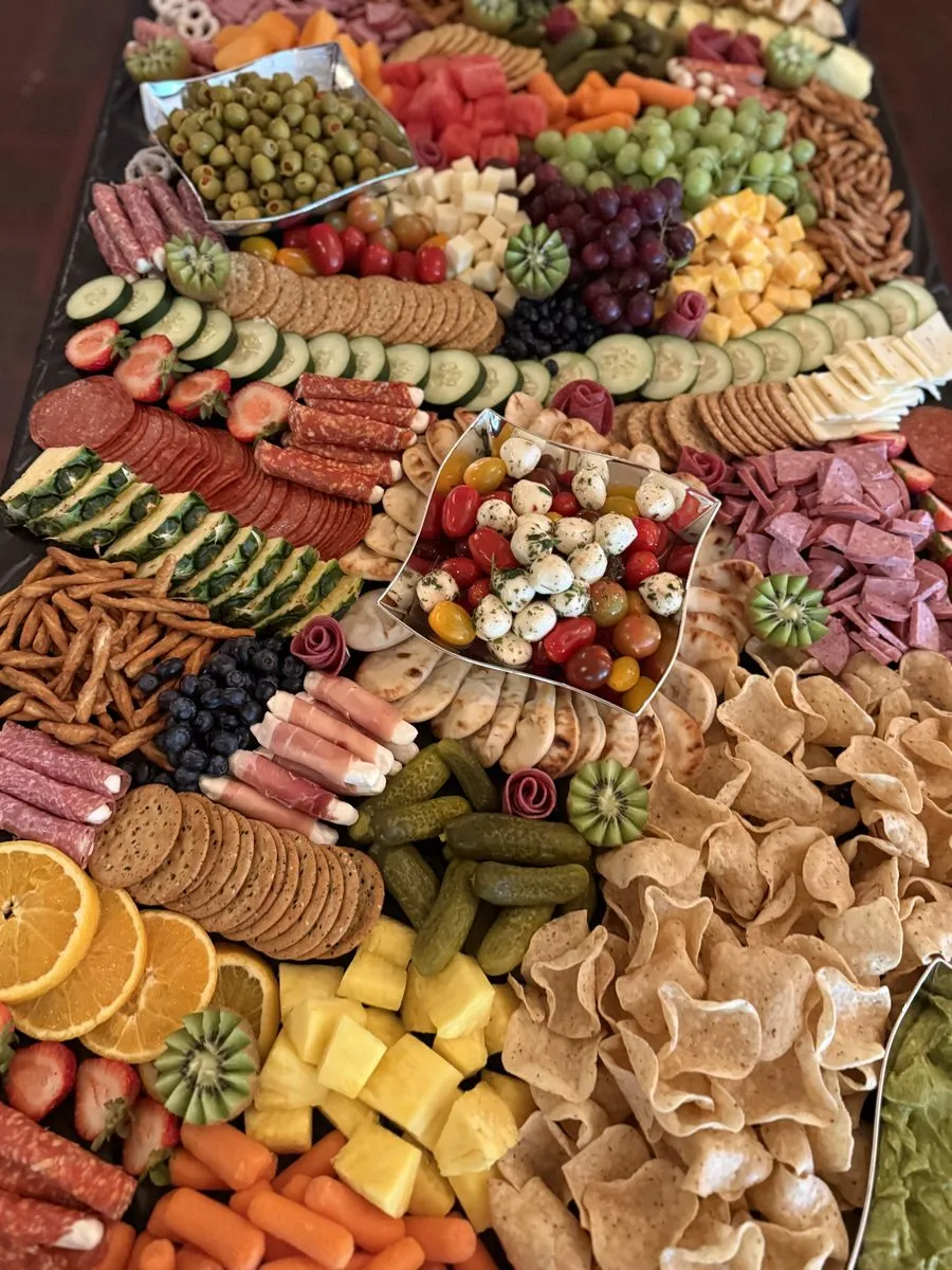 Grazing table detail with marinated mozzarella and tomato skewers, cucumbers, orange slices and pretzels