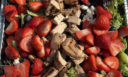 Strawberry salad with grilled chicken, blueberries, feta and mixed greens in a catering tray